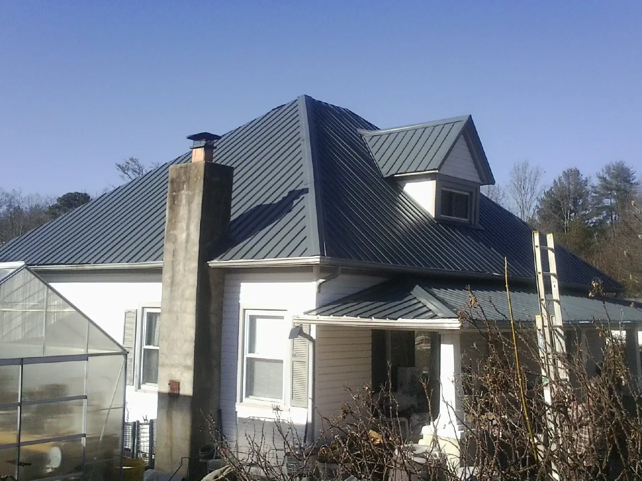 Dark blue standing seam metal roof on a white farmhouse with dormer — Slate & Tile Roof Repair by Roofing Brothers in Coplay