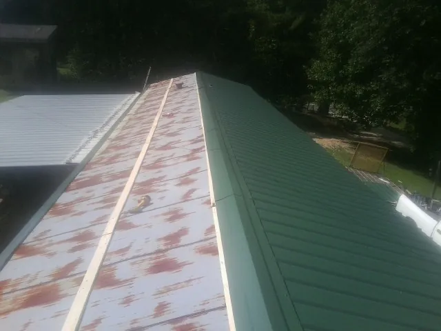 Old rusted panels beside newly installed green metal roofing — Wind Damage Roof Repair by Roofing Brothers in Coplay