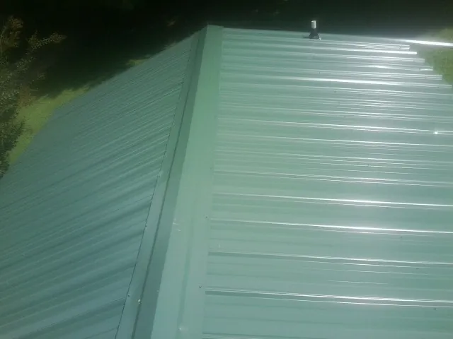 New green metal panels meeting at the ridge of a roof — Flat Roof Repair work by our crew in Coplay