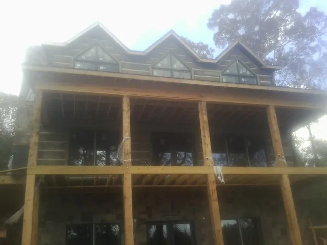 Dormers and porch framing on a large log home under construction — Roof Coating work by our crew in Coplay