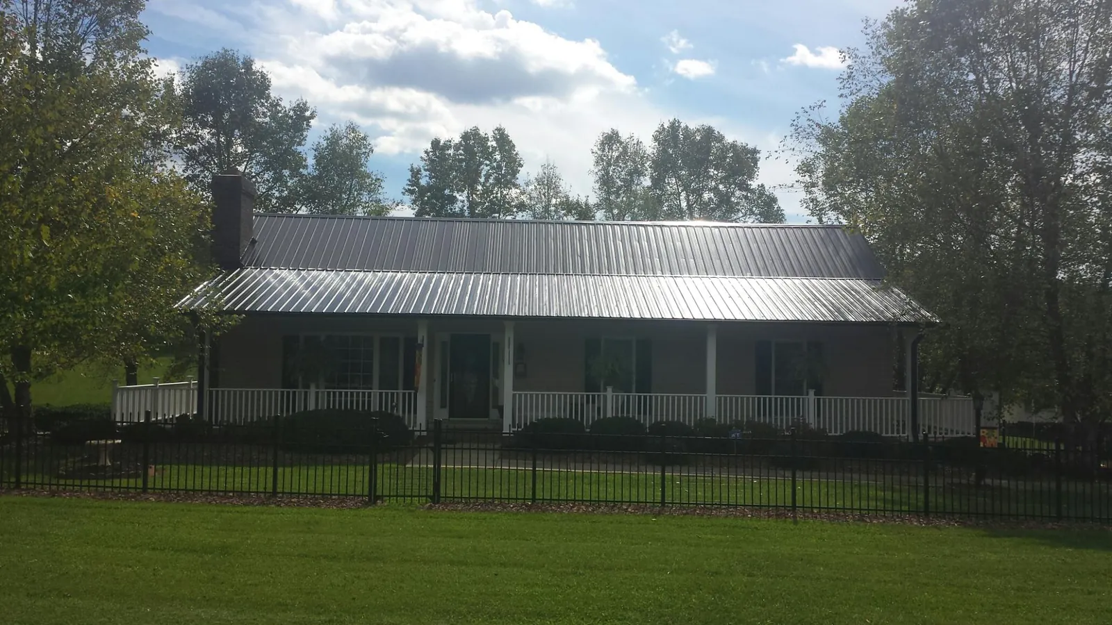 Gray metal roof on a brick ranch with a full width front porch — Gutter Guard Installation work by our crew in Coplay