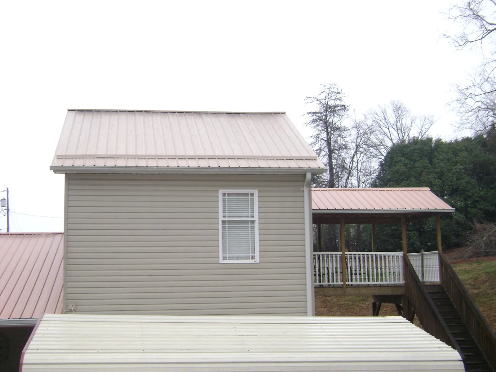 Tan metal roofs on a two story addition and attached porch in Coplay
